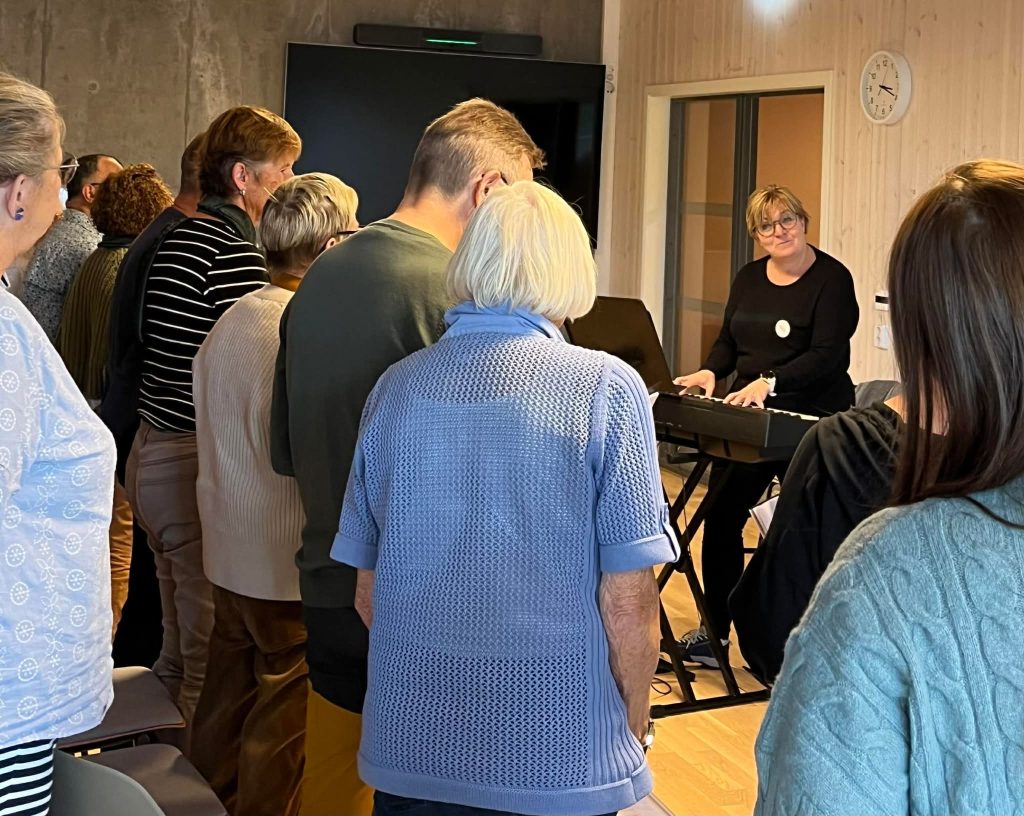 Ingrid som spiller piano foran Demenskoret Grønnresept