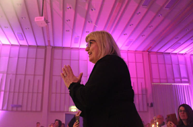 sideprofil av Ingrid som dirigerer, med rosa bakgrunn