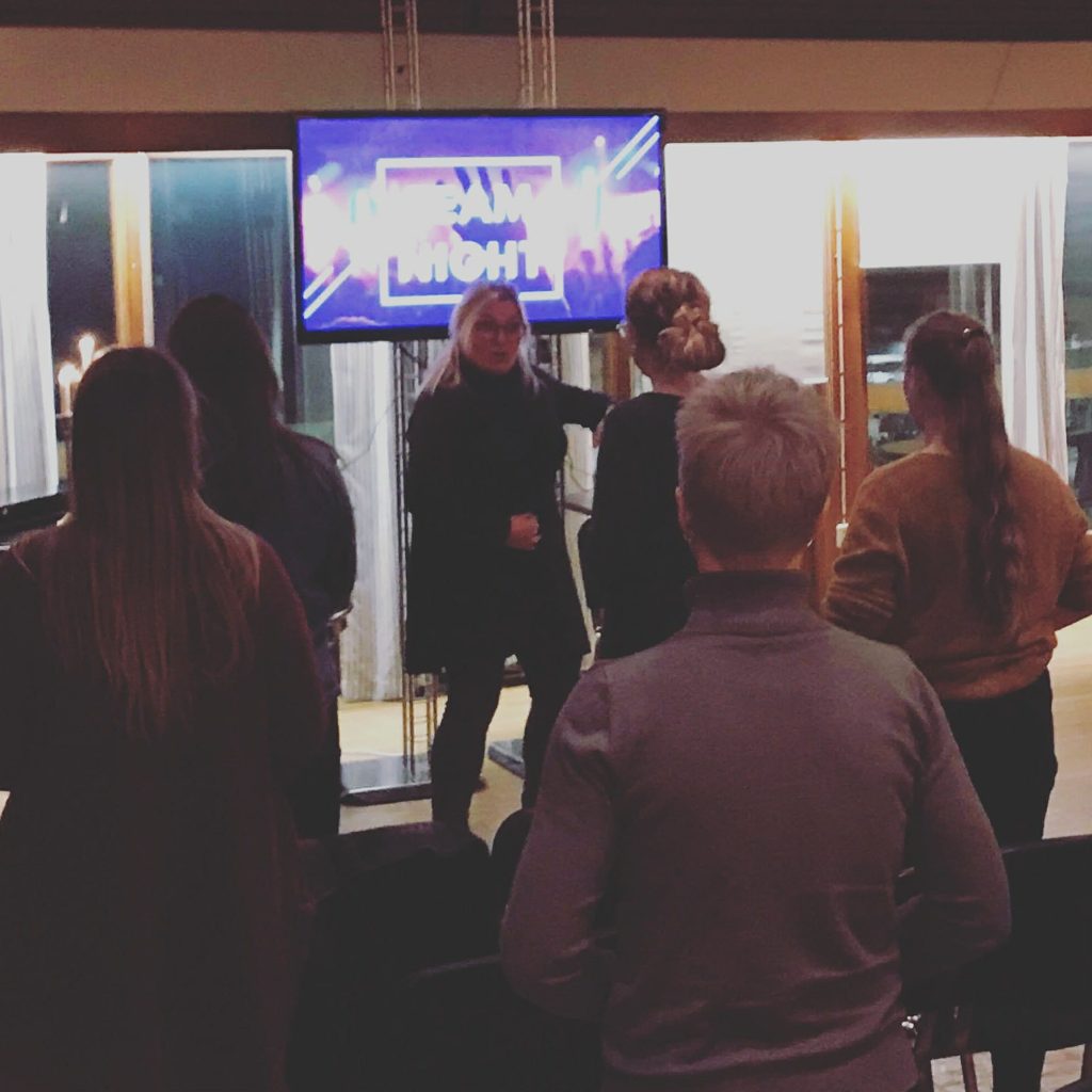 Ingrid foran en TV og flere mennesker